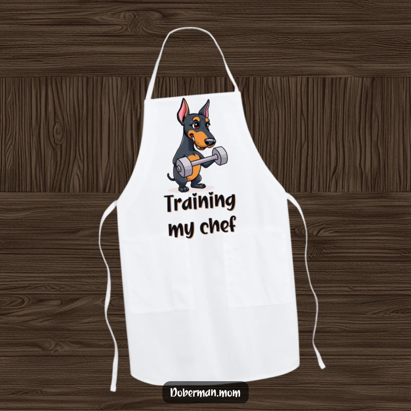 Funny Doberman apron featuring a determined dog ready to train, even in the kitchen, balancing a tiny dumbbell.
