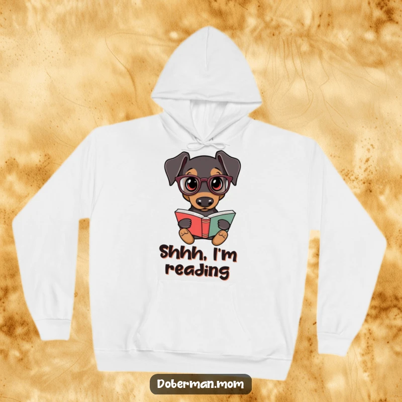 Funny Doberman Intellectual Hoodie: A Doberman dog dons tiny reading glasses and a book, showcasing a love for learning humorously.