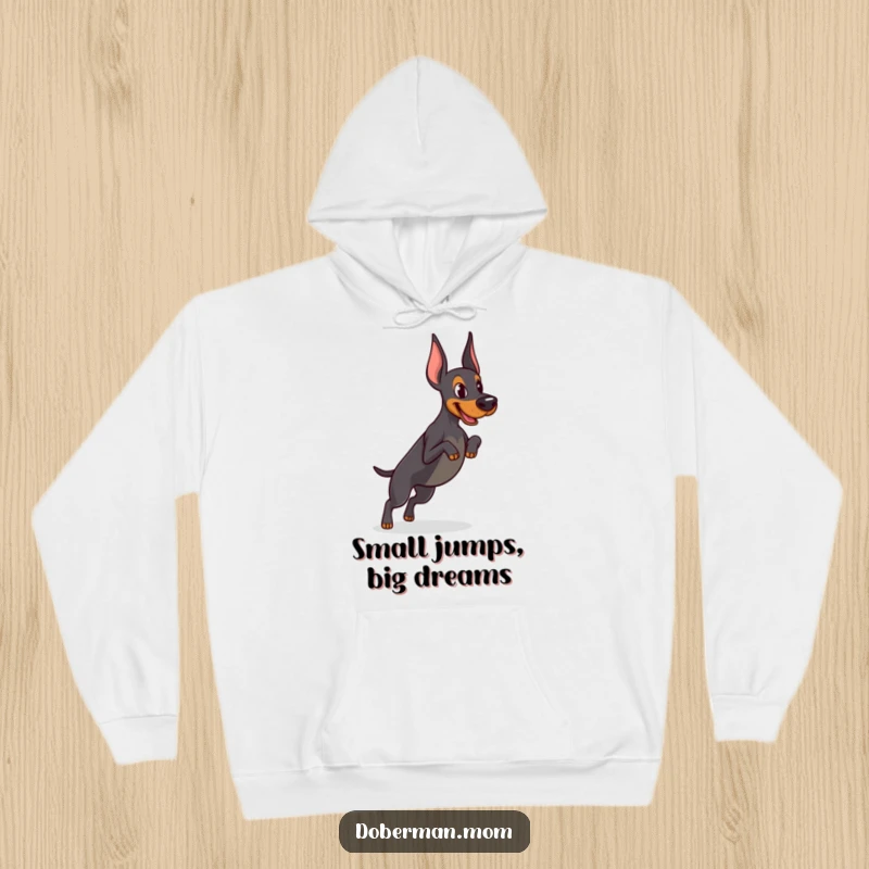 Funny Determined Doberman hoodie showing focused practice of a tiny jump, offering athletic warmth and humorous motivation for training.
