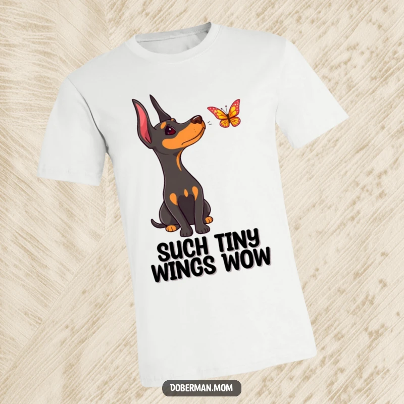 Funny Doberman t-shirt, depicting a dog with a curious head tilt, captivated by a fluttering butterfly's flight.